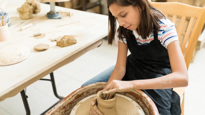 woman throwing clay on a wheel